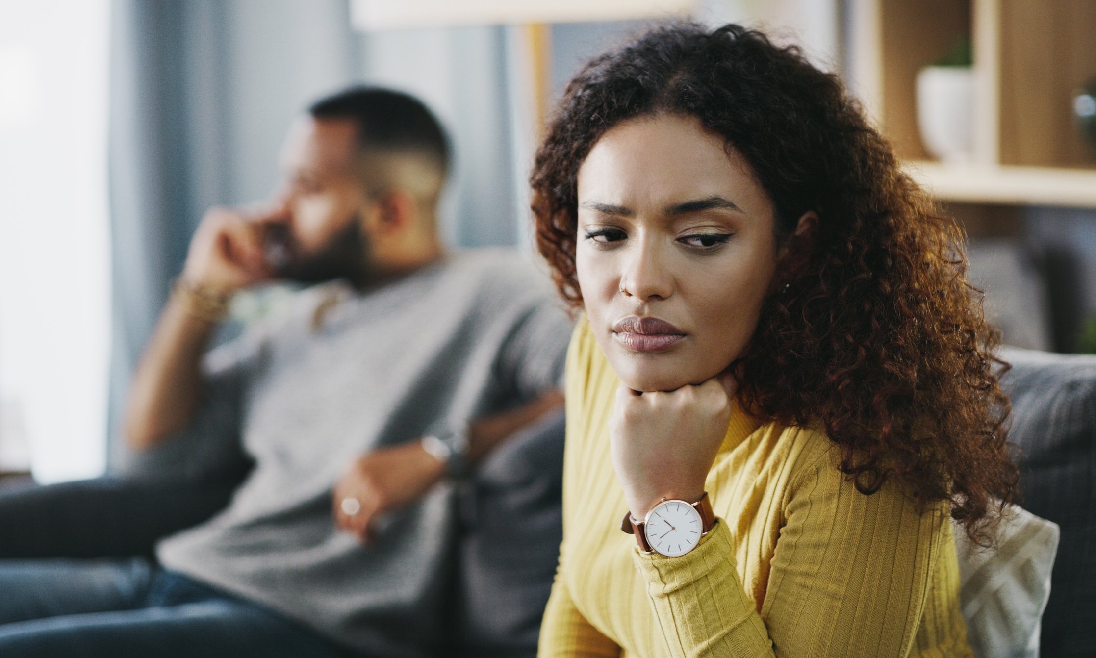 Black couple sitting apart on the couch - infertility