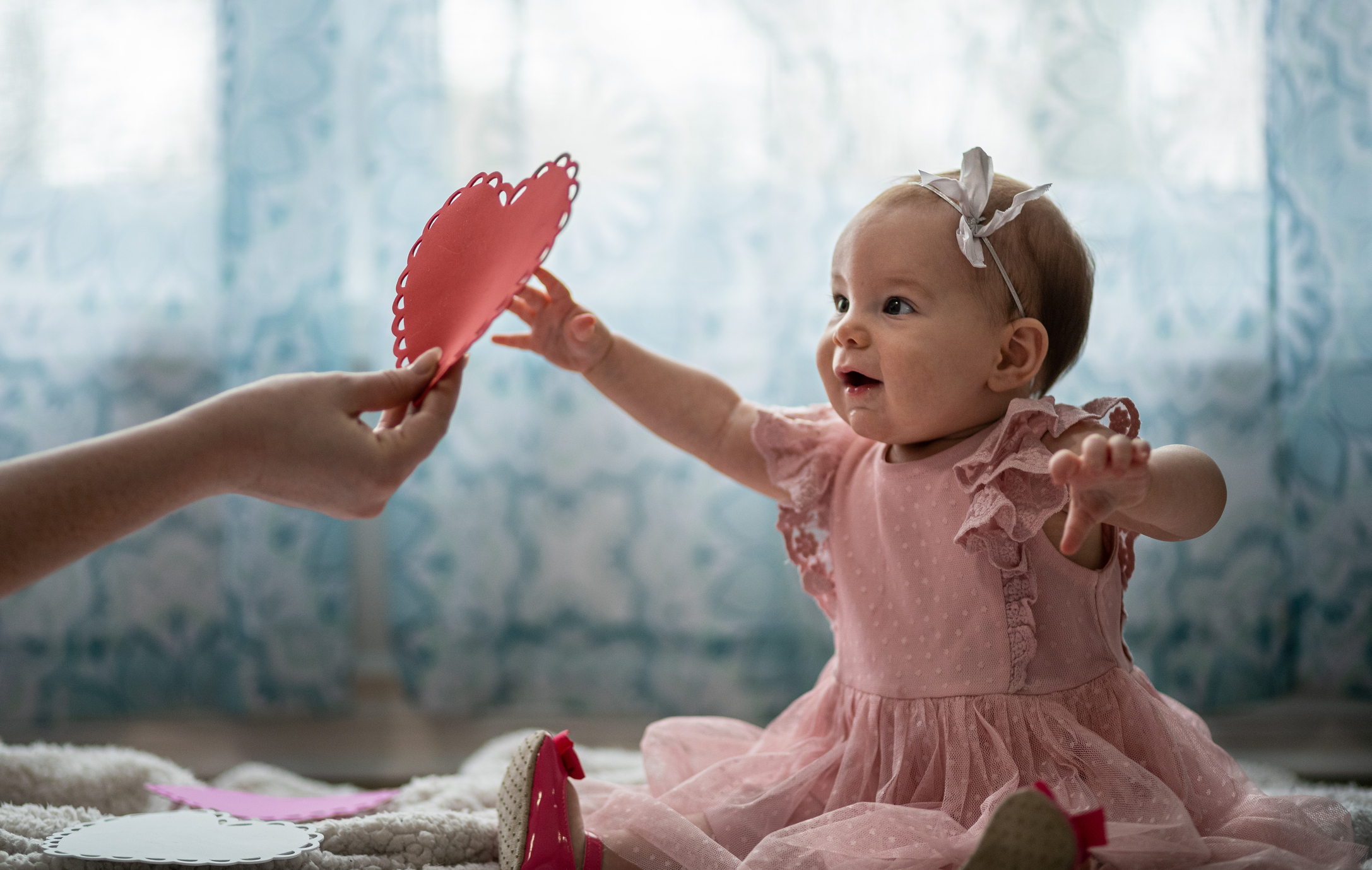 A cute baby girl dressed in pink is enjoying a Valentines day photo shoot