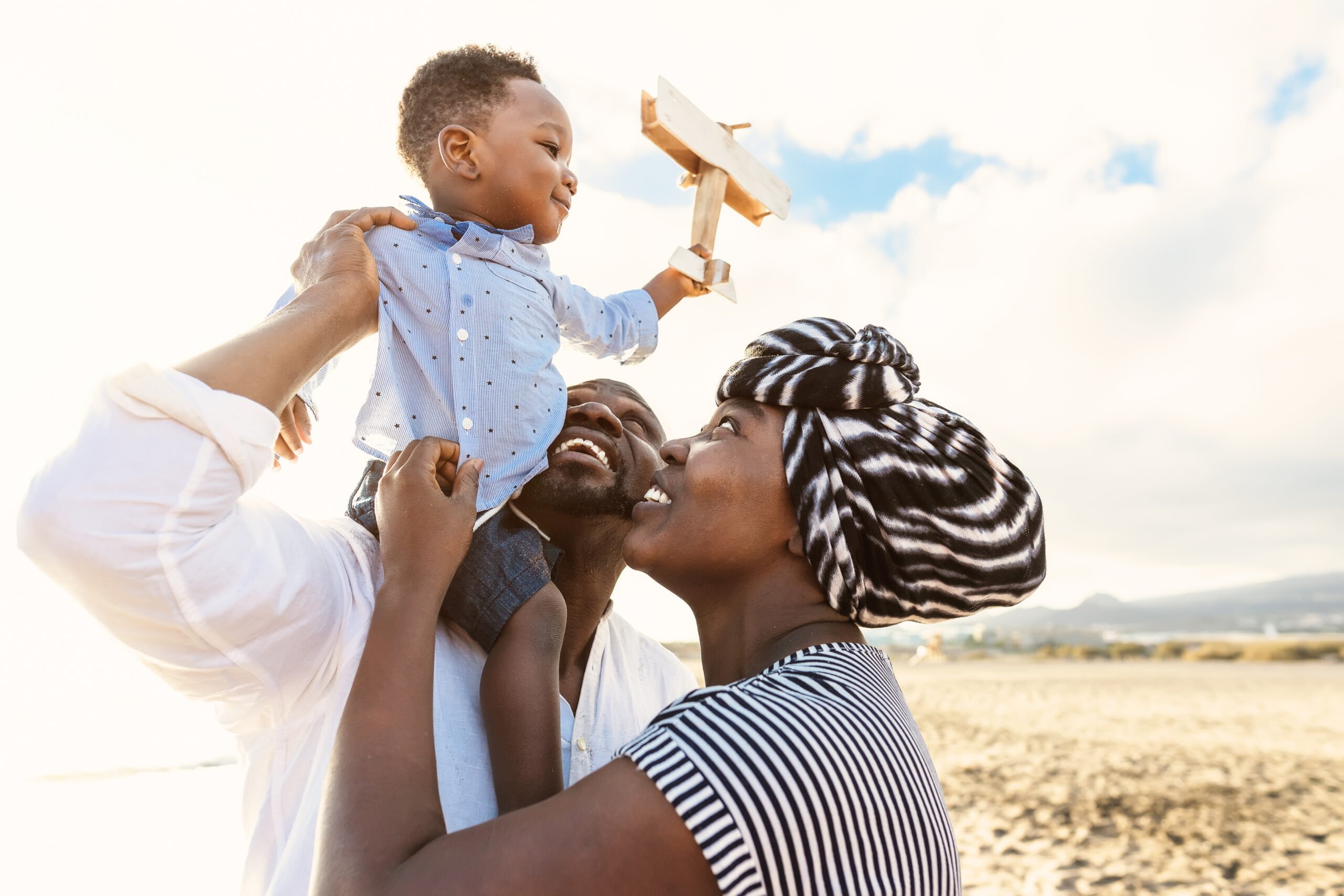Happy African family having fun on the beach during summer vacation - Parents love and unity concept