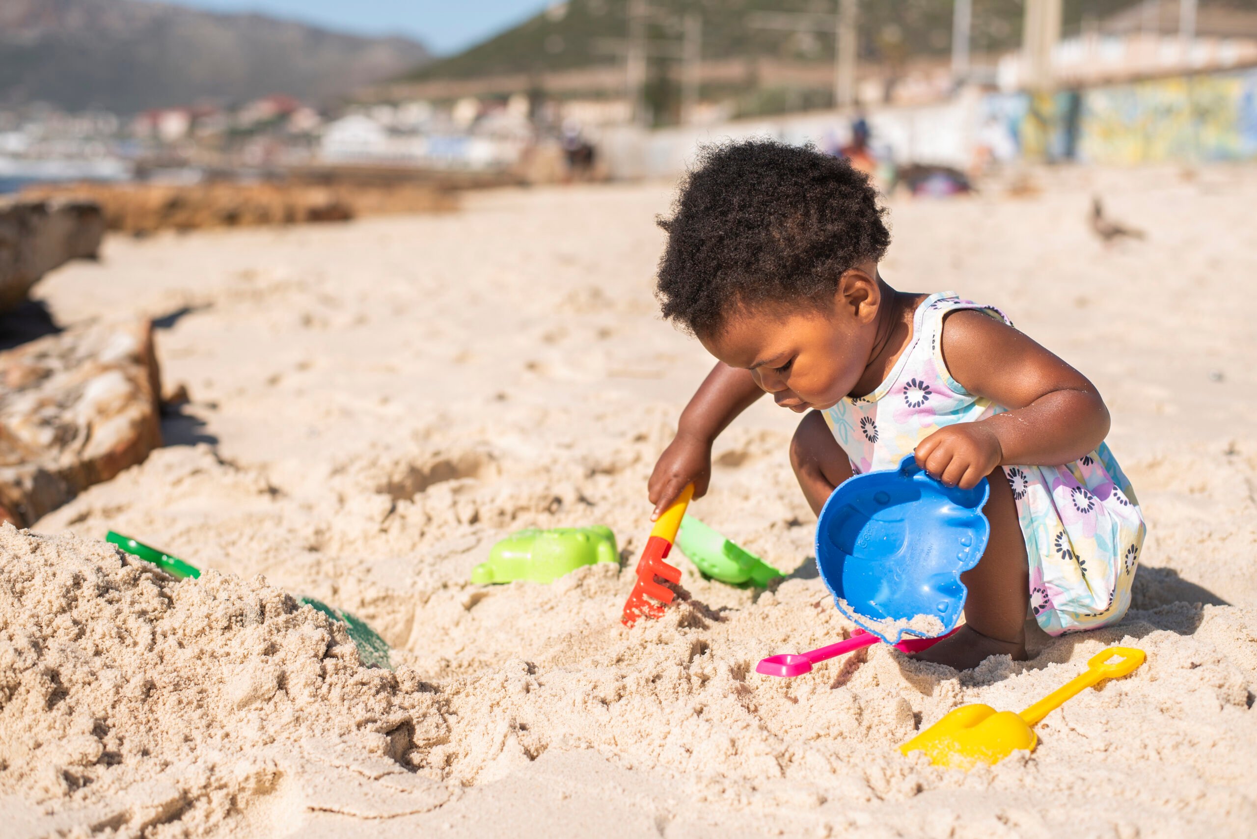 Little girl playing with a sand pail and shovel at the beach