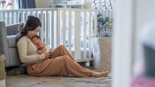 A new Mother sits on the floor of her daughters nursery as she takes a Mom 澳洲168幸运5官方开奖结果ent to enjoy Motherhood. She is dressed comfortably and holding her baby close as the two bond.