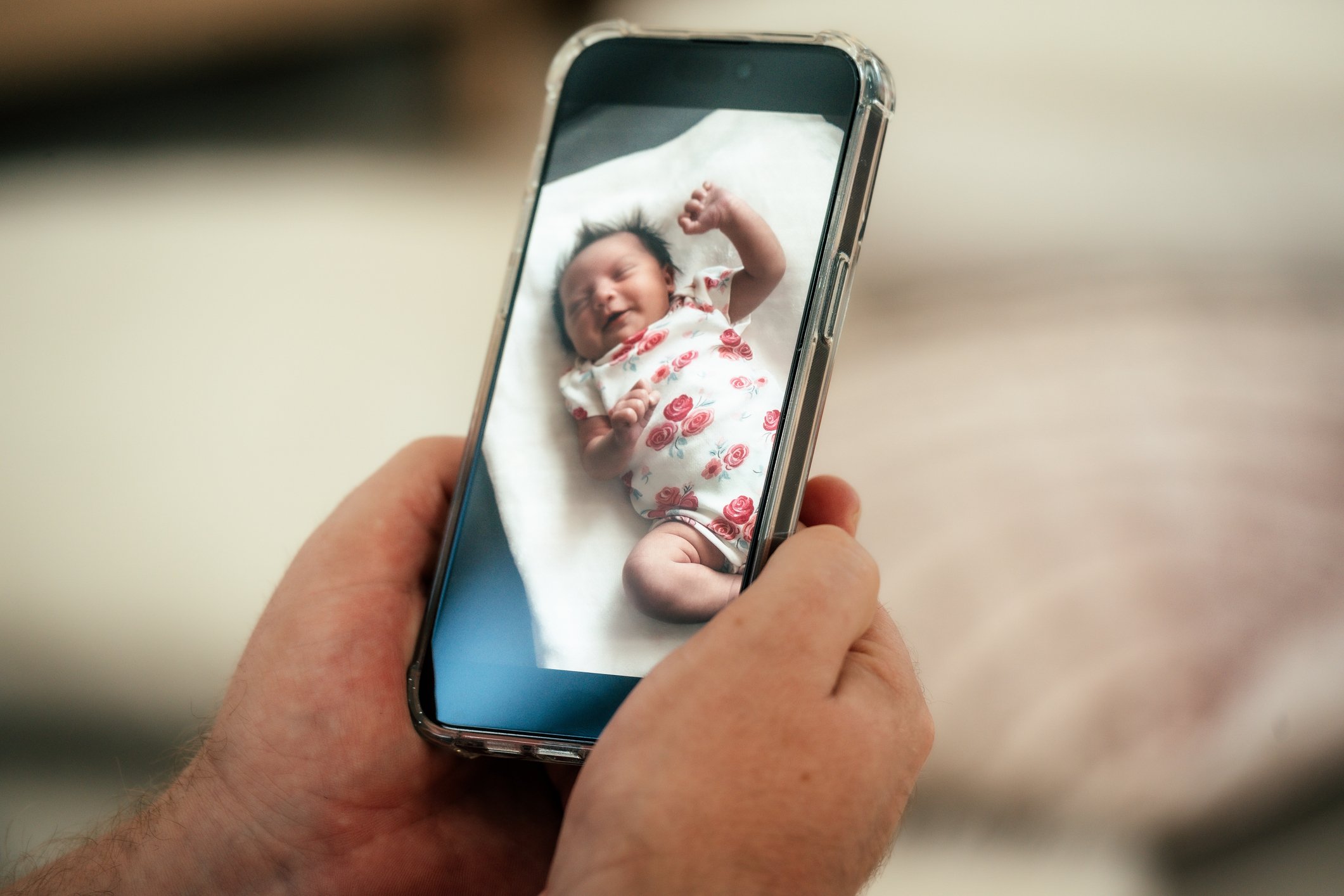 Father using newborn girl baby smart monitor on his mobile phone at home