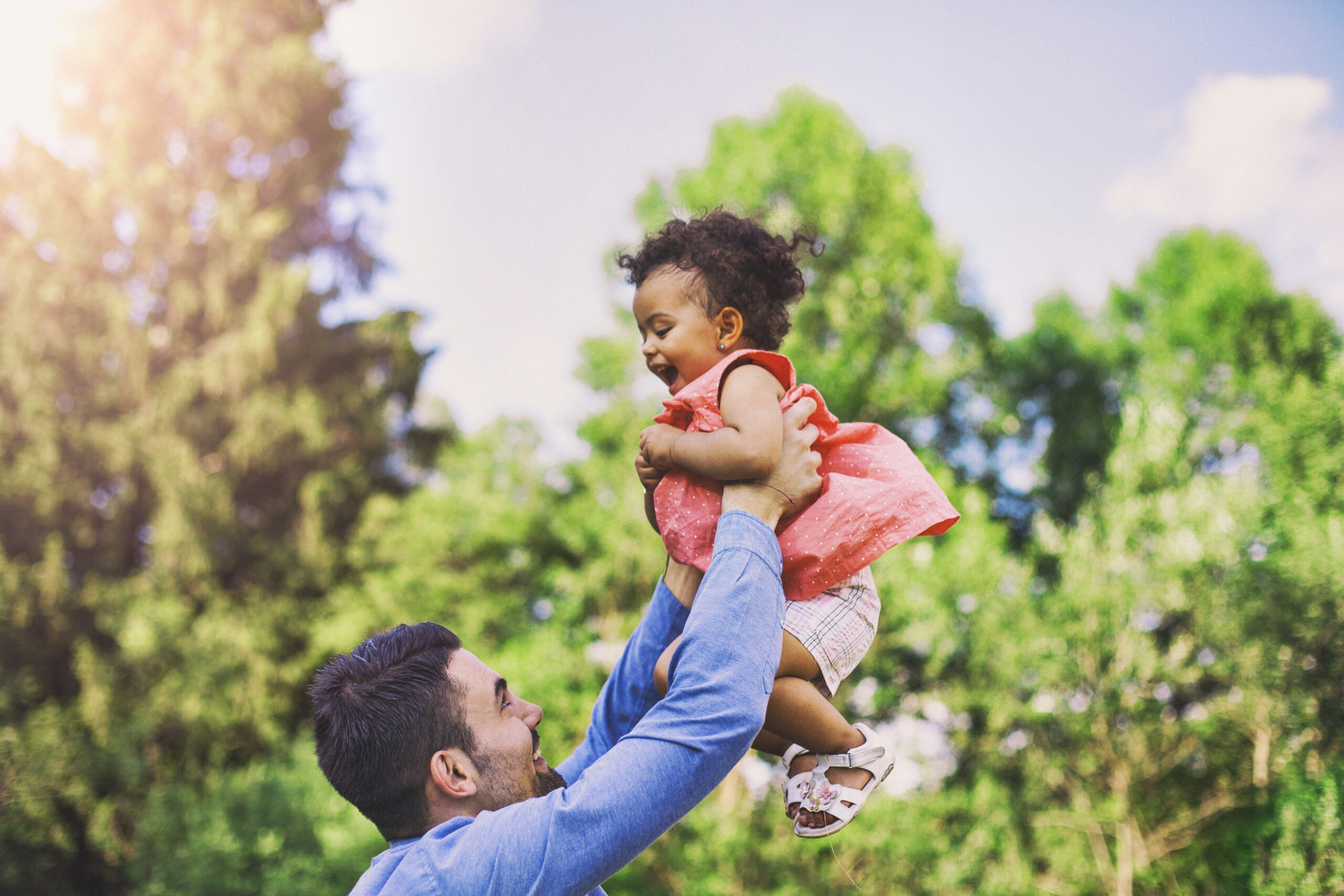 Father throwing his baby daughter in the air in a park