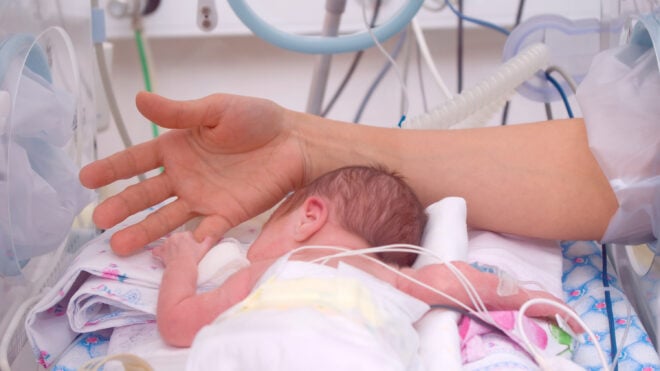 Hand of the physician and newborn in incubator in hospital